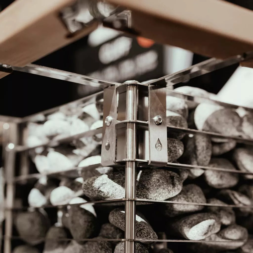 Zoomed in image of top corner of Huum cliff sauna heater showing rocks against the steel frame and wooden safety rail