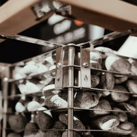 Zoomed in image of top corner of Huum cliff sauna heater showing rocks against the steel frame and wooden safety rail