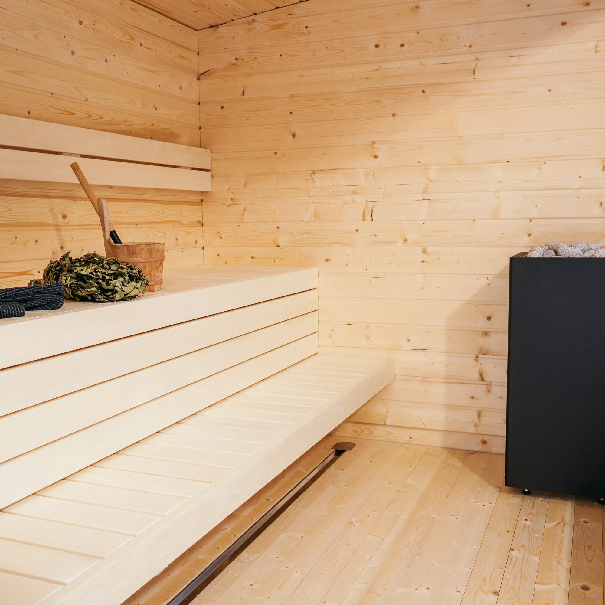 Huum Core black sauna heater in corner of pine coloured sauna