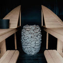 Huum Hive sauna heater set back in a black coloured sauna with light wood benches