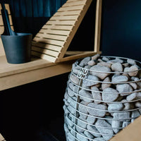 Side view of Huum Hive sauna heater in black sauna with light wooden benches