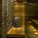 huum hive mini sauna heater  positioned near a stone wall in a small sauna