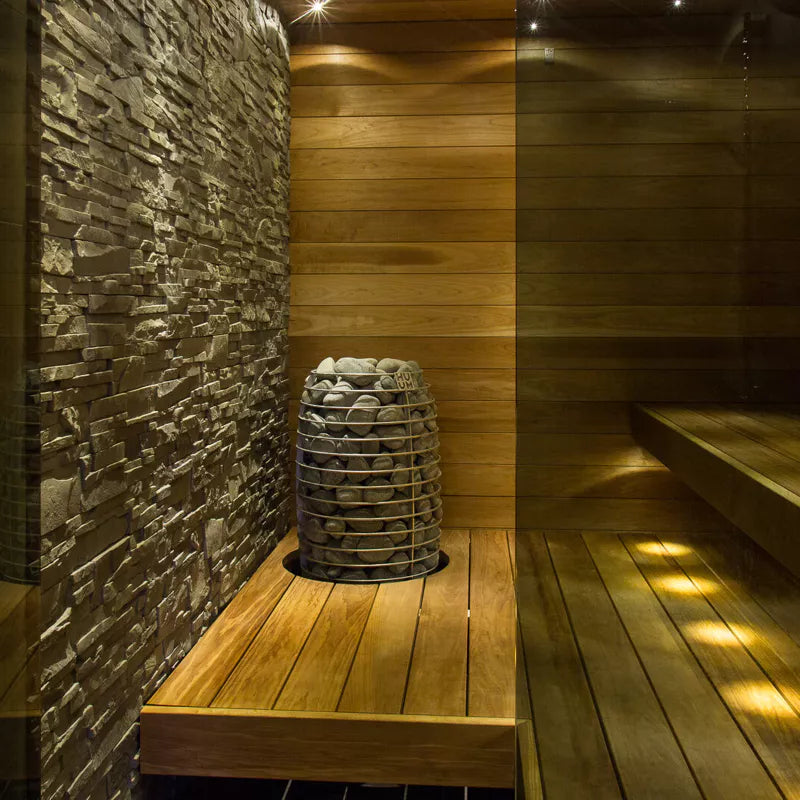 huum hive mini sauna heater  positioned near a stone wall in a small sauna