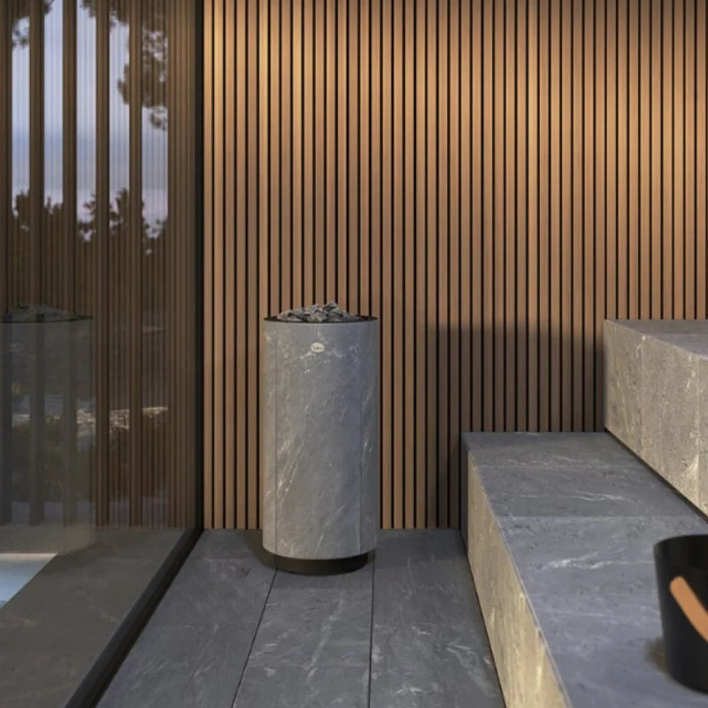 Modern sauna setting with a cylindrical grey sauna heater against a wooden slat wall.