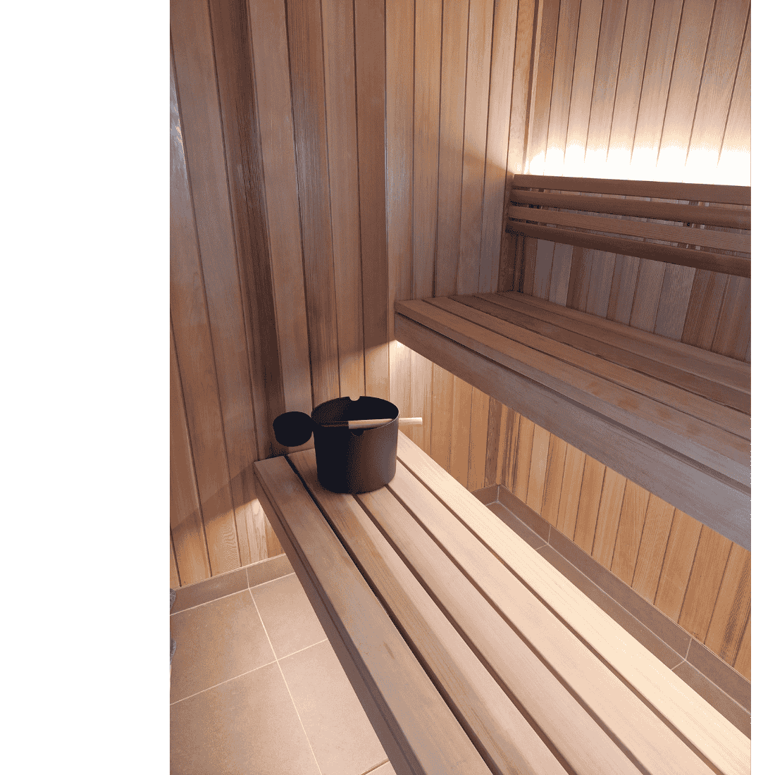 Wooden sauna with benches and a bucket on a tiled floor.
