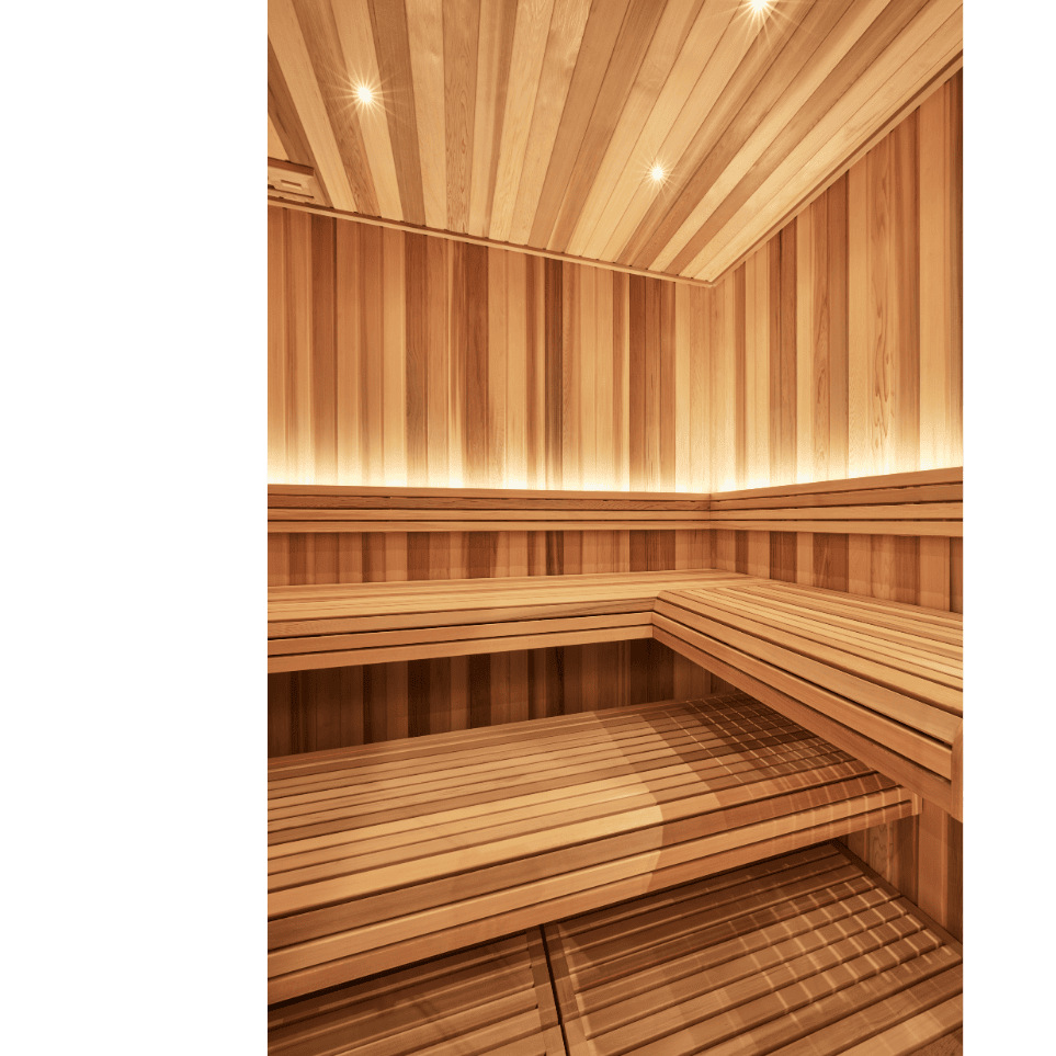 Well lit sauna interior with light coloured timber lining the walls and ceiling