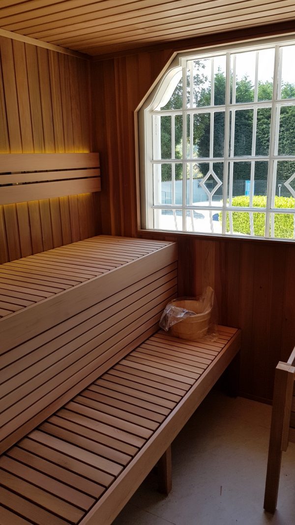 Wooden sauna with a bench and a window showing greenery outside