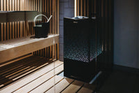 Tylo Crown combi elite sauna heater against wall of heater with built-in lights glowing through aluminium grill