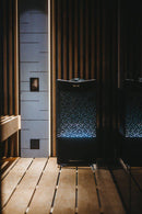 Tylo Crown elite electric sauna heater on floor in moodily lit sauna